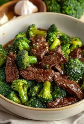 Beef and broccoli stir-fry served on a white plate with colorful vegetables