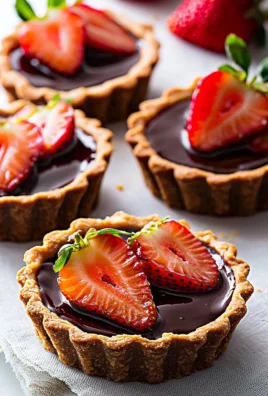 Delicious chocolate strawberry tarts topped with fresh strawberries and chocolate sauce