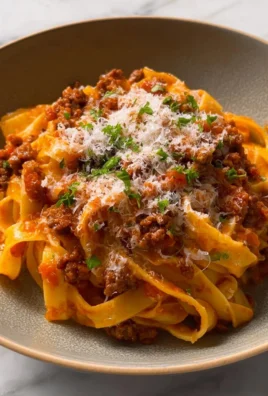 Creamy Fettuccine Bolognese served in a bowl with fresh herbs on top