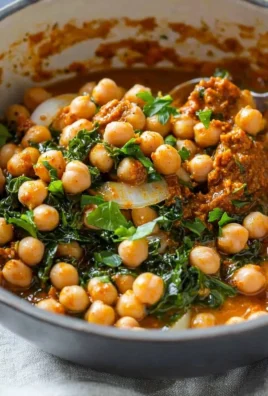 A bowl of spicy Harissa Chickpeas garnished with fresh herbs.