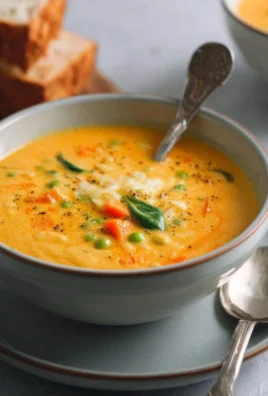 Bowl of hearty creamy vegetable soup with fresh vegetables and herbs