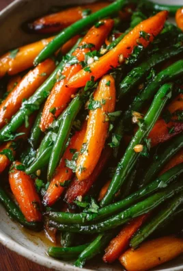 Honey glazed carrots and green beans served on a plate garnished with herbs.