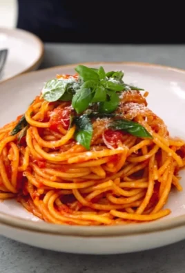 A plate of fresh tomato pasta garnished with basil and parmesan cheese