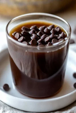 Homemade chocolate chip cookie dough syrup in a glass jar with chocolate chips
