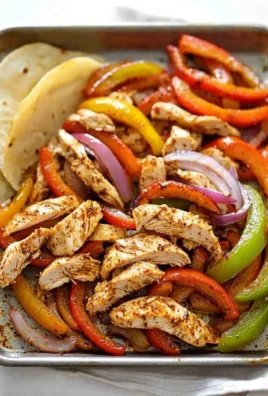 Sheet Pan Chicken Fajitas with colorful peppers and spices on a baking tray
