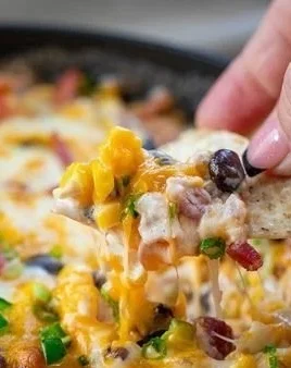 Cheesy Baked Cowboy Dip served in a baking dish with tortilla chips on the side