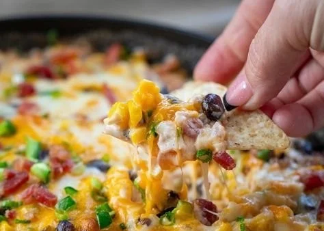 Cheesy Baked Cowboy Dip served in a baking dish with tortilla chips on the side
