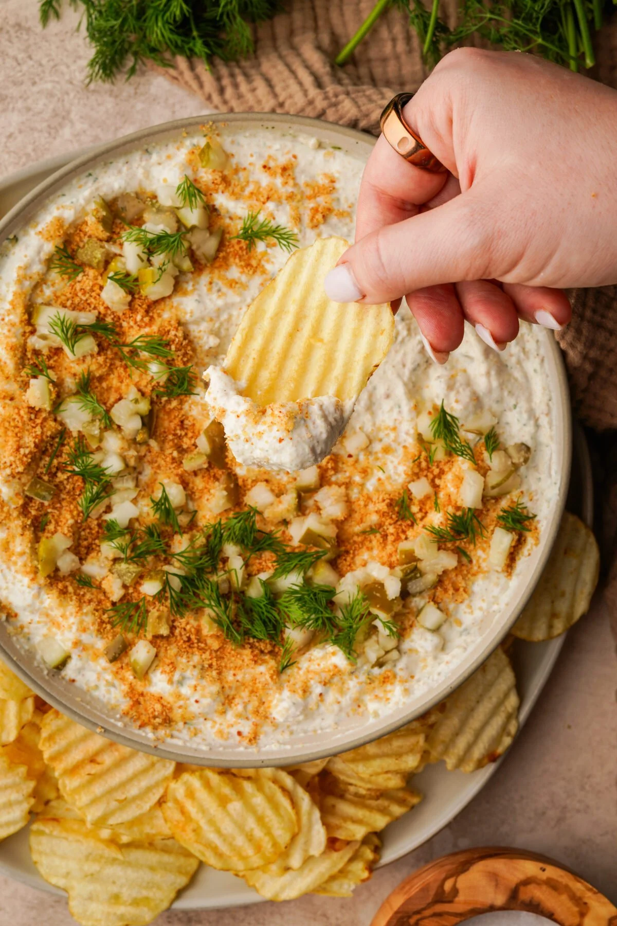 Creamy fried pickle dip served in a bowl with chips and pickles on the side.