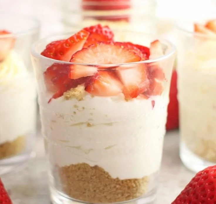 Delicious no-bake cheesecake cups topped with fresh berries and whipped cream.